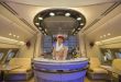 Cabina di prima classe Emirates con hostess sorridente al bar di bordo, simbolo del lusso contrapposto al low cost di Ryanair nella battaglia sui social.